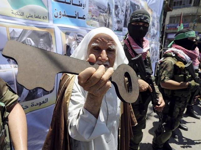 A Palestinian man holds a symbolic key next to Hamas militants during a rally after Nakba Day in Rafah in the southern Gaza Strip
