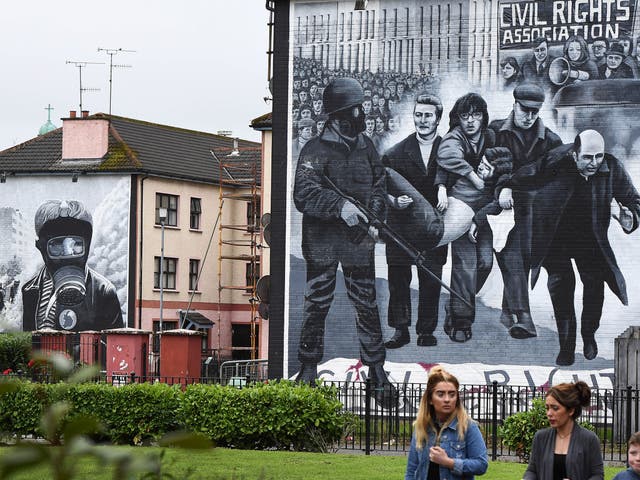 A family walks past a mural depicting a scene from Bloody Sunday