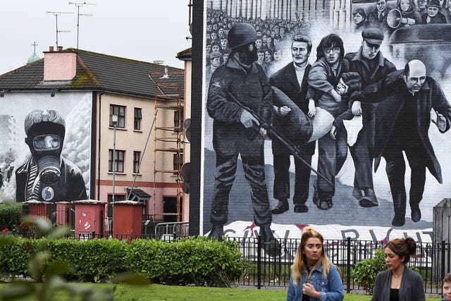 A family walks past a mural depicting a scene from Bloody Sunday