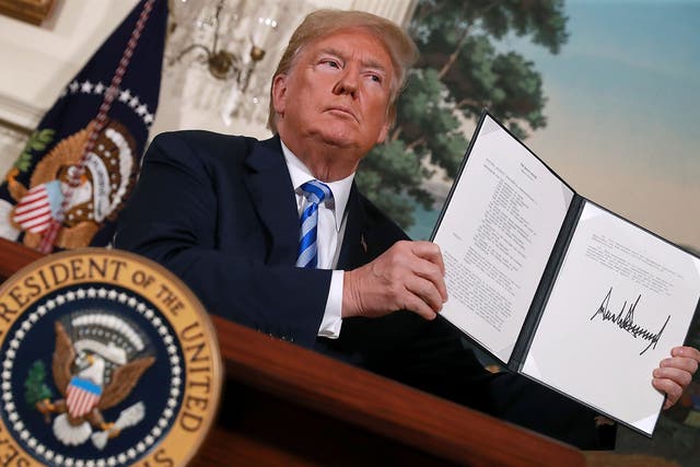 President Donald Trump holds up a memorandum that reinstates sanctions on Iran after he announced his decision to pull out the US from the 2015 Iran nuclear deal
