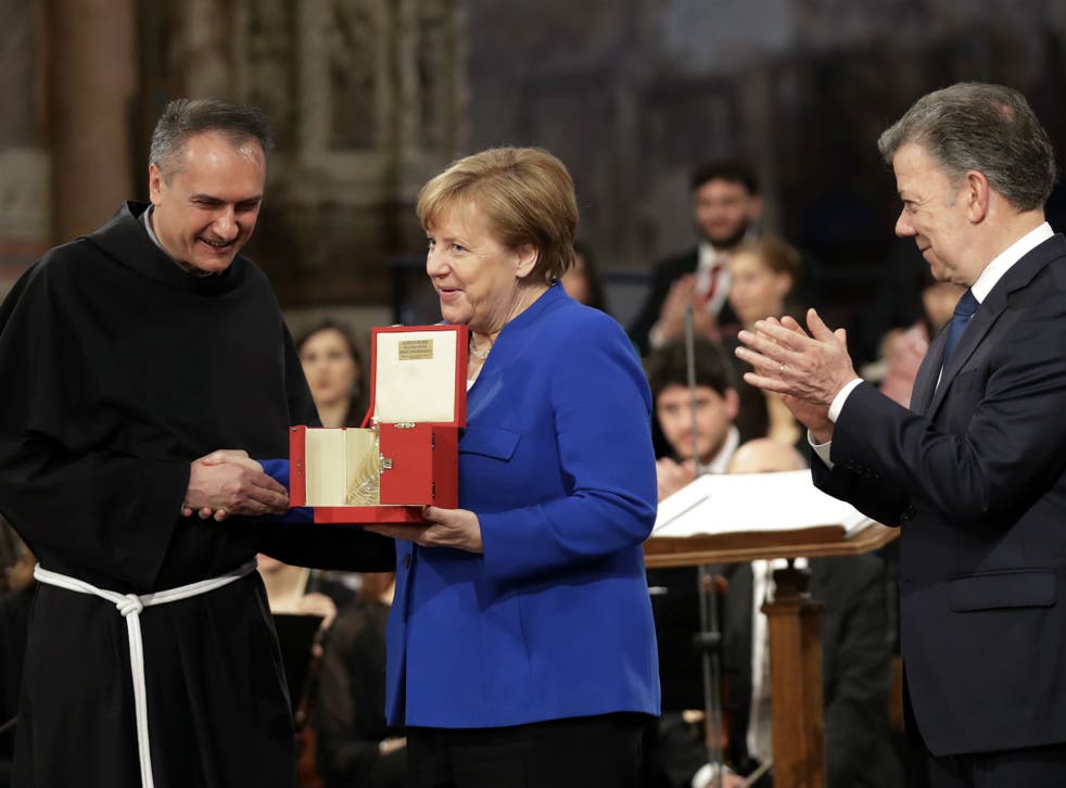 German Chancellor Angela Merkel, centre, flanked by Colombian President Juan Manuel Santos, right, receives the St. Francis lamp peace prize by Father Mauro Gambetti