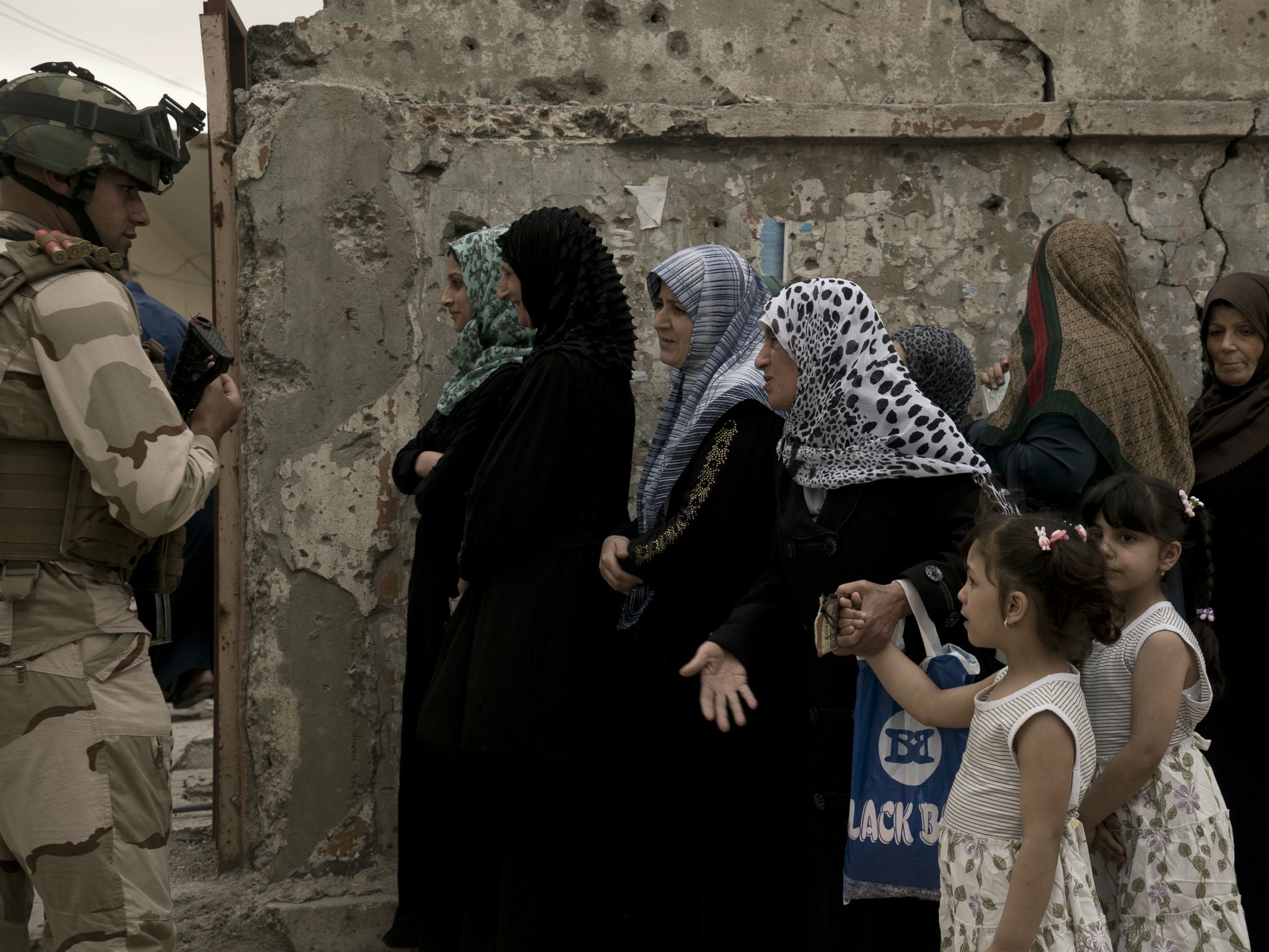 Iraqi women line up to to cast their vote in the country’s parliamentary elections at a polling site in a damaged building in West Mosul