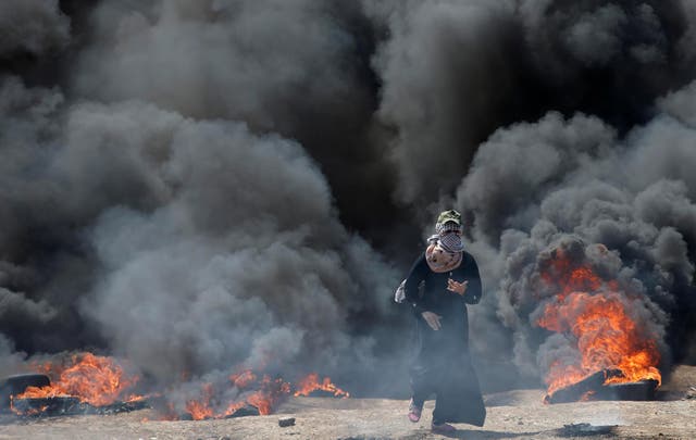 A Palestinian demonstrator runs during a protest against the US embassy move to Jerusalem and ahead of the 70th anniversary of the Nakba at the Israel-Gaza border on 14 May 2018