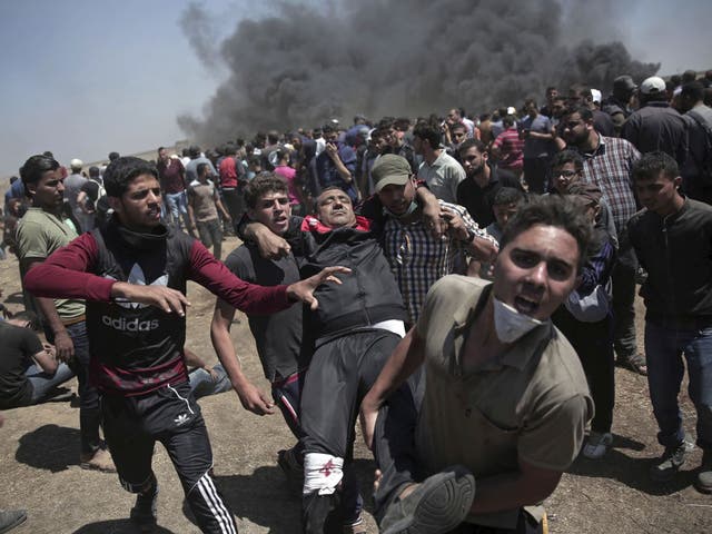 Palestinian protesters carry an injured man who was shot by Israeli troops during a deadly protest at the Gaza Strip's border with Israel, east of Khan Younis, 14 May