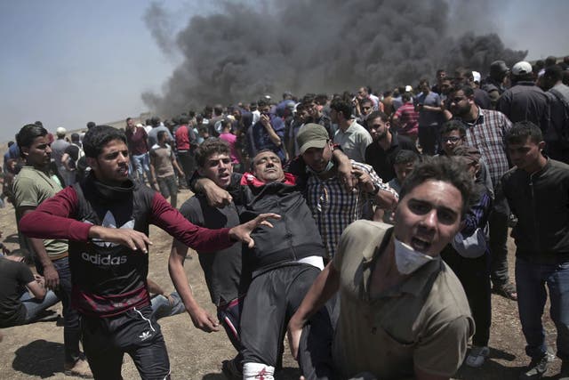 Palestinian protesters carry an injured man who was shot by Israeli troops during a deadly protest at the Gaza Strip's border with Israel, east of Khan Younis, 14 May