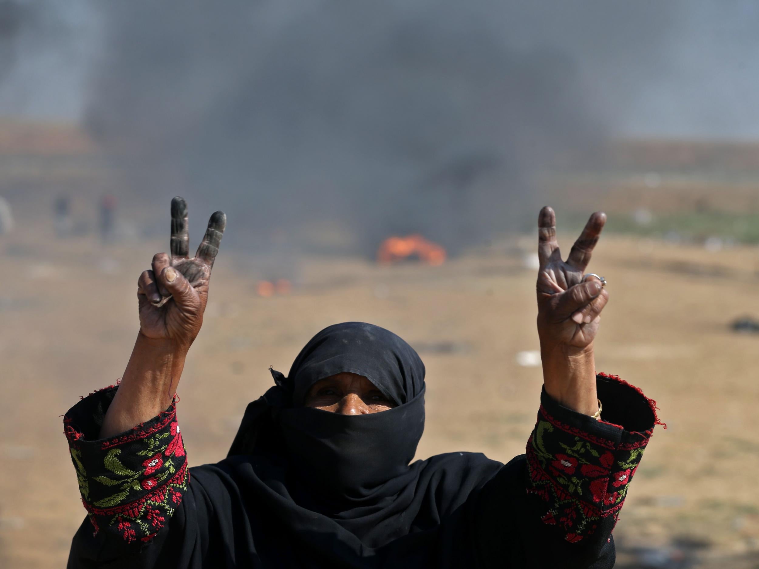 A Palestinian woman flashes the V for victory sign during protest near the border fence on 15 May