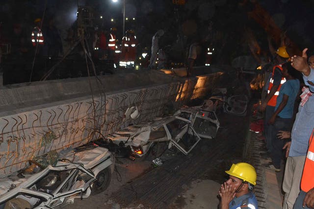 Rescue workers prepare to remove a beam as vehicles are seen trapped under the rubble after a part of an under construction flyover collapsed in Varanasi, India