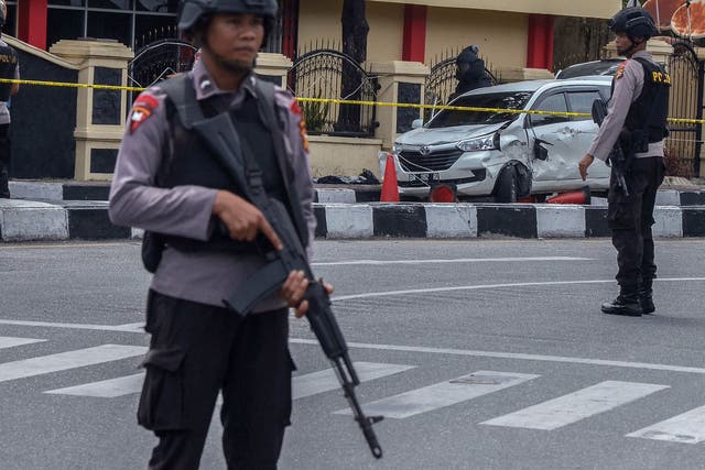 Police stand guard as a car that was used to attack the police headquarters is examined in Pekanbaru