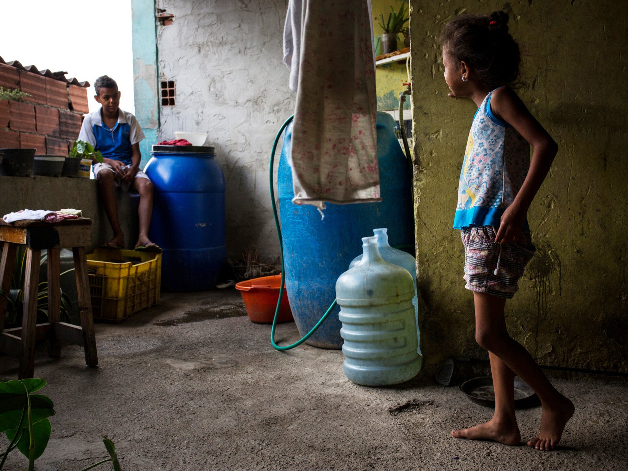 A child stands in front of water containers in Guarenas, Venezuela
