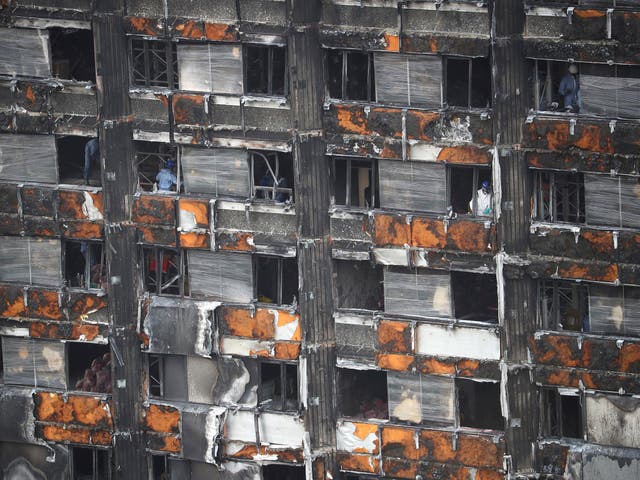 Workers stand inside the burnt out remains of the Grenfell tower