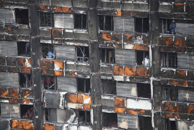 Workers stand inside the burnt out remains of the Grenfell tower