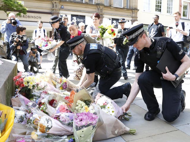 Police officers laying flowers in St Ann's Square, Manchester, the day after a suicide bomber killed 22 people, including children, as an explosion tore through fans leaving a pop concert in Manchester