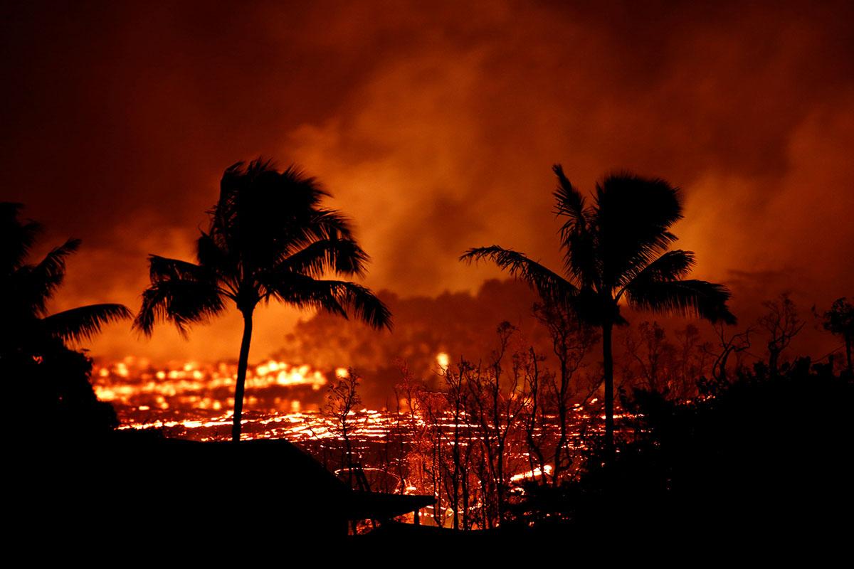 Lava flows past trees on the outskirts of Pahoa during ongoing eruptions of the Kilauea Volcano in Hawaii