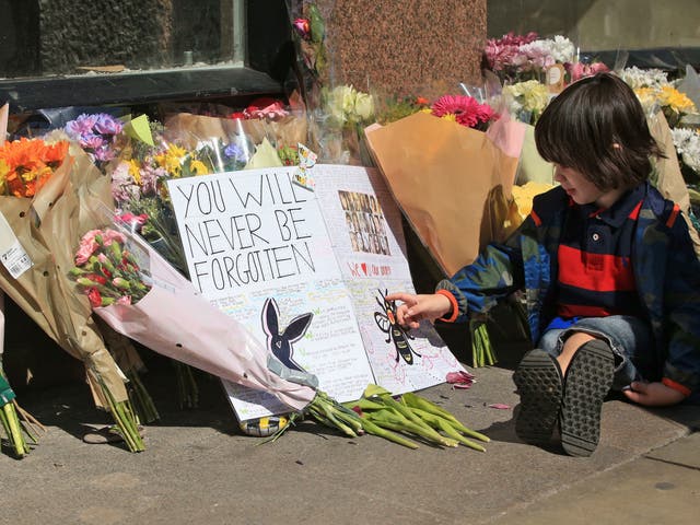 Felix, two,sits next to messages and flowers left in Manchester, ahead of the Manchester Arena National Service of Commemoration at Manchester Cathedral to mark one year since the Manchester attack.