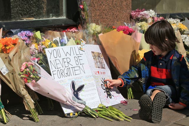 Felix, two,sits next to messages and flowers left in Manchester, ahead of the Manchester Arena National Service of Commemoration at Manchester Cathedral to mark one year since the Manchester attack.