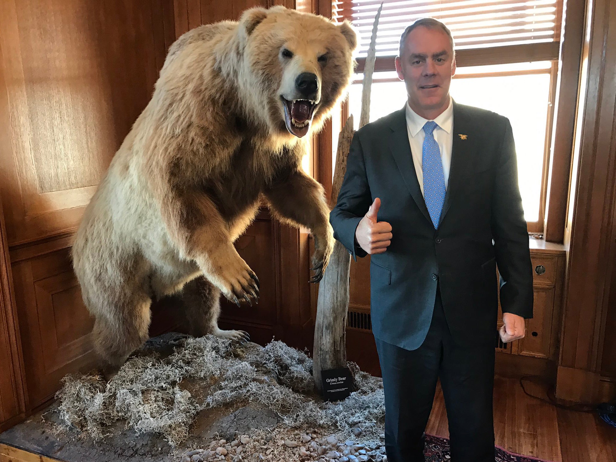 US interior secretary Ryan Zinke poses alongside a taxidermied grizzly bear