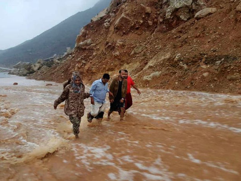 Men walk on a road flooded after heavy rain and strong winds caused damage in Hadibu as Cyclone Mekunu pounded the Yemeni island of Socotra
