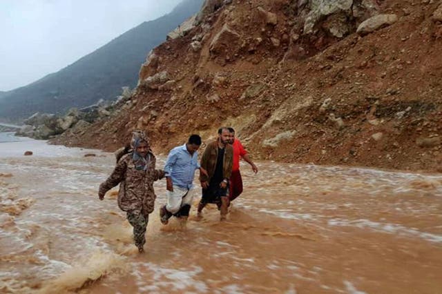 Men walk on a road flooded after heavy rain and strong winds caused damage in Hadibu as Cyclone Mekunu pounded the Yemeni island of Socotra