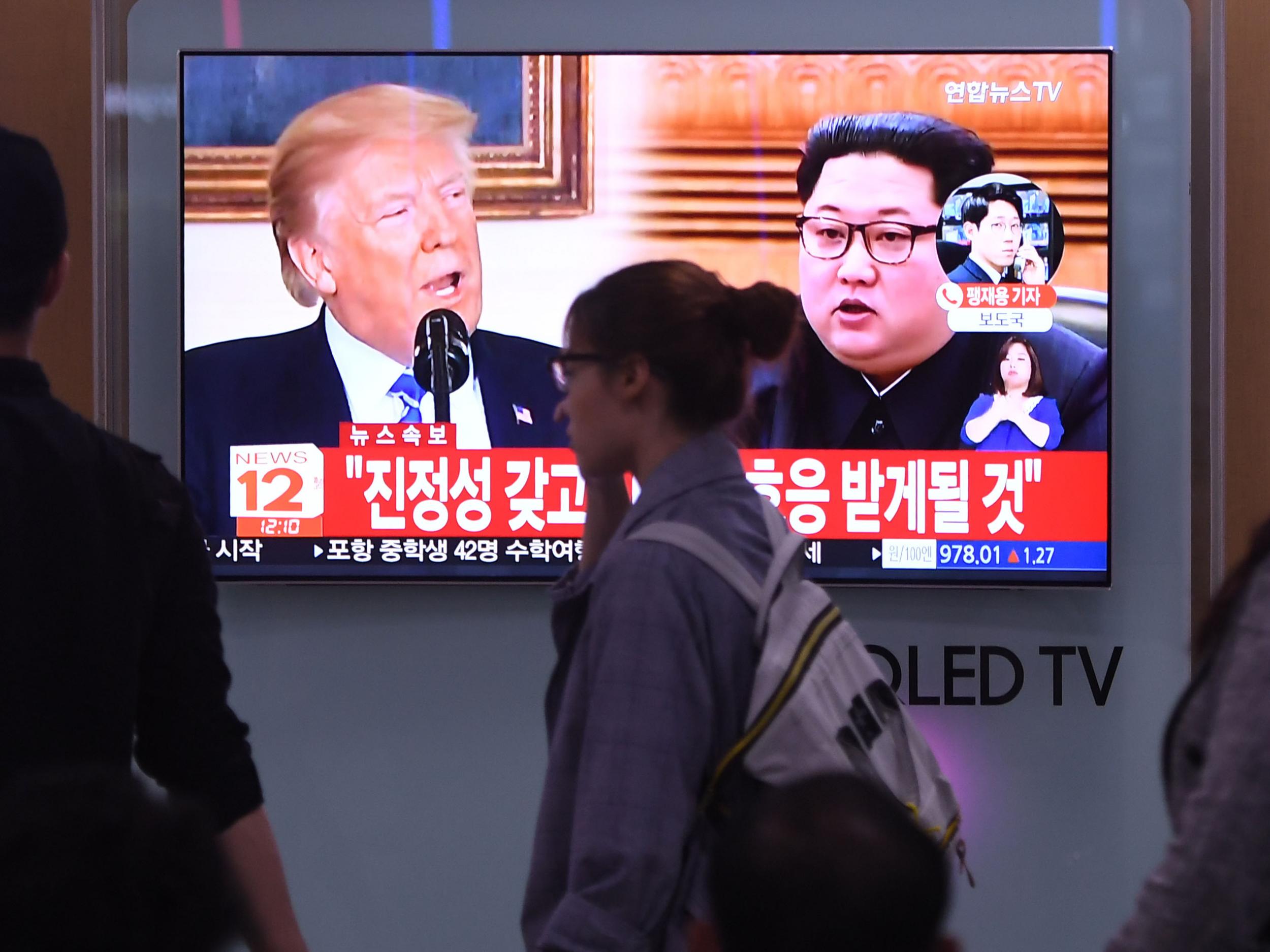 People walk past a television news screen showing North Korean leader Kim Jong Un