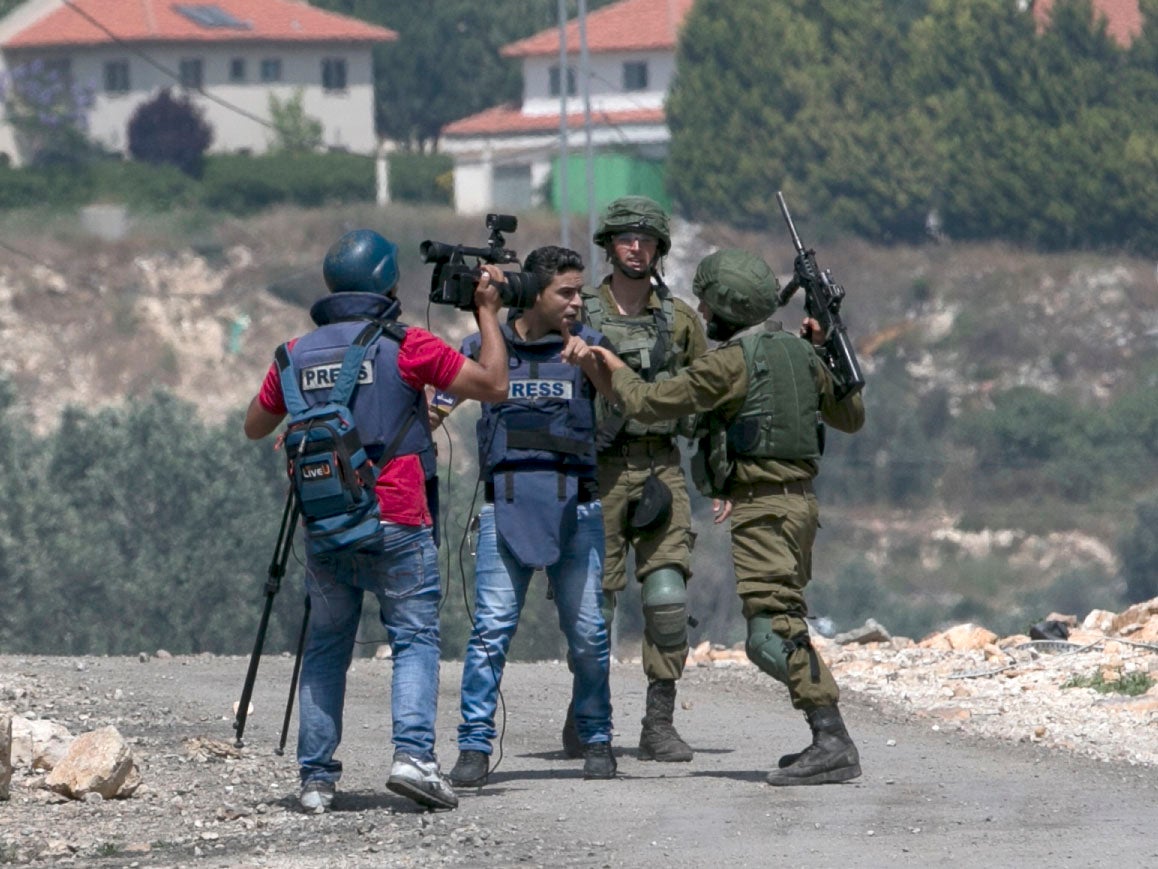 An Israeli soldier escorts a Palestinian journalist as Palestinian protesters clash with Israeli forces during a weekly demonstration against the expropriation of Palestinian land by Israel in the village of Kfar Qaddum, near Nablus in the occupied West Bank, on May 11, 2018