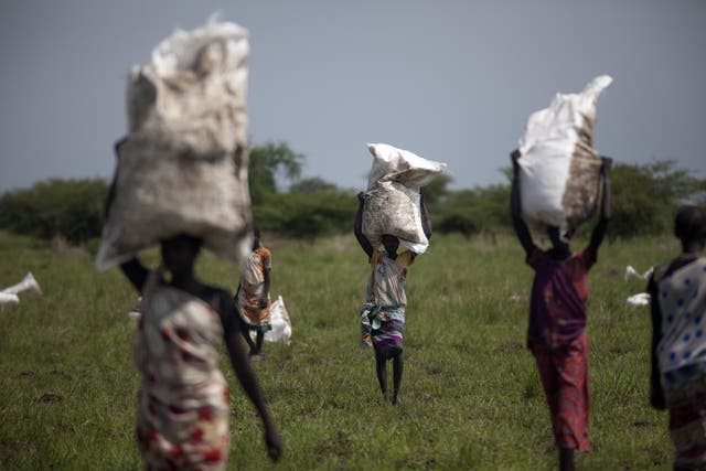 Women carry sacks of food airdropped by the World Food Programme and distributed by Oxfam in South Sudan