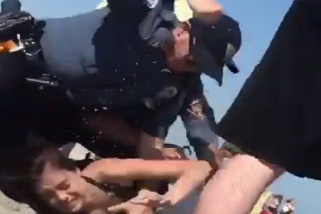 A video showed a police officer punching a woman in the head while trying to arrest her for underage drinking in Wildwood, New Jersey.