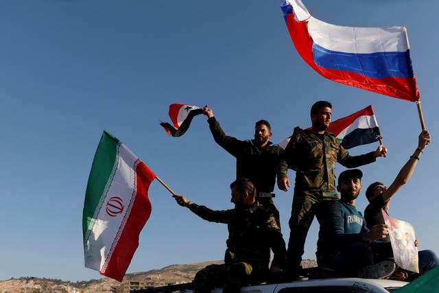 Syrians wave Iranian, Russian and Syrian flags during a 14 April 2018 protest against US-led air strikes in Damascus