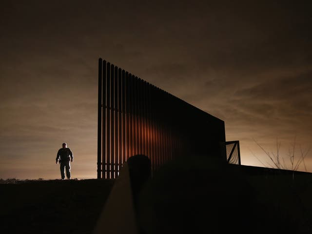 A US Border Patrol agent stands near a section of the US-Mexico border fence