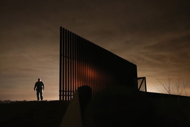 A US Border Patrol agent stands near a section of the US-Mexico border fence