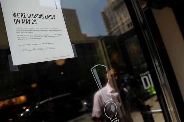 A sign in the window of a door of a Starbucks explains the store will close early for racial bias training