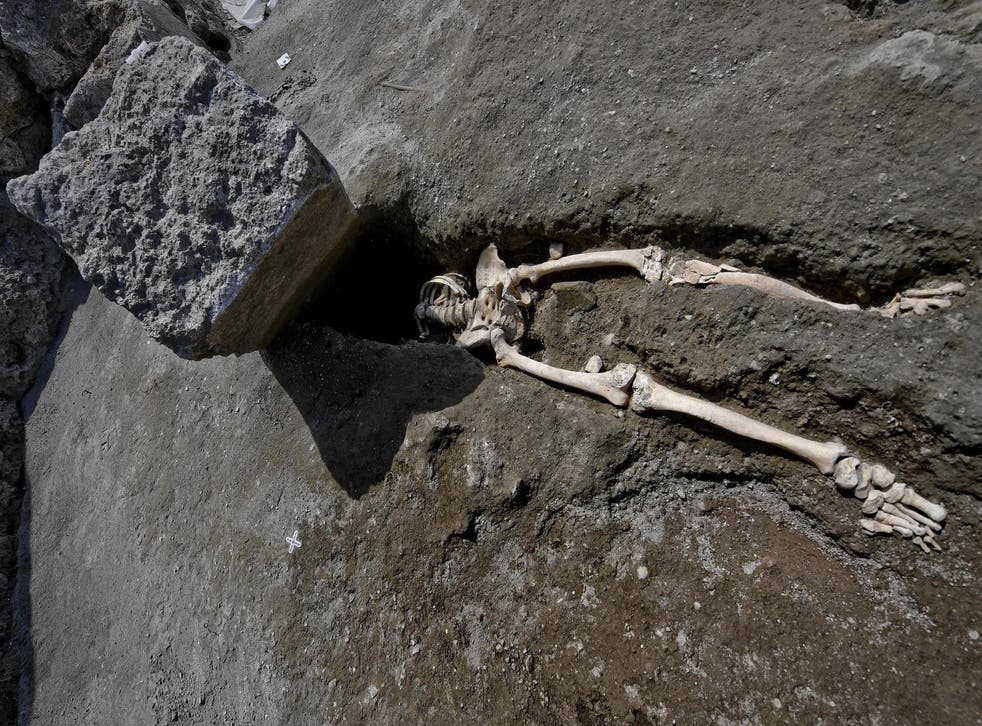 The skeleton was found sprawled beneath a large block of stone which covered where its head would have been. Ciro Fusco/EPA