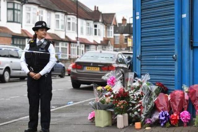 A police officer stands by floral tributes left in Tottenham, north London, for 17-year-old girl Tanesha Brown, who was shot dead