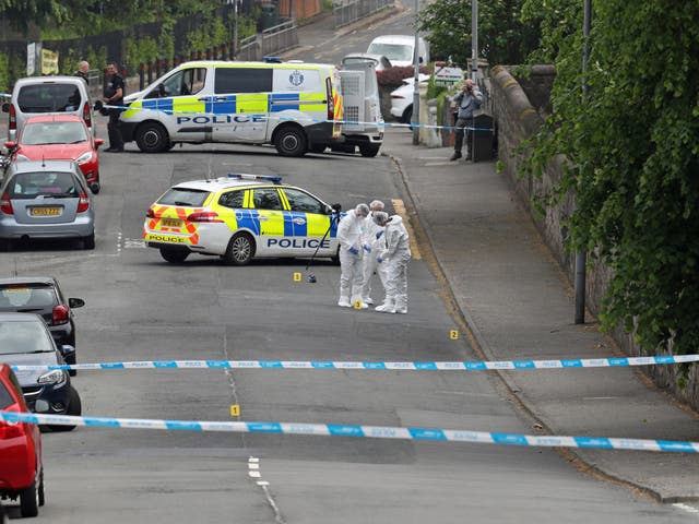Forensic officers put a knife in an evidence bag as they investigate the scene of an incident in Gateside Gardens, Greenock, where two police officers were injured