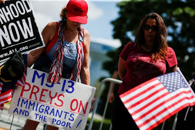A Donald Trump supporter holds a banner against the MS-13 gang ahead of an appearance by the president