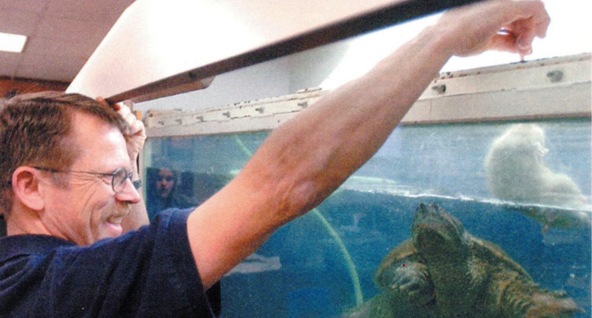 Robert Crosland dangles a rat in the turtle tank at Preston Junior High