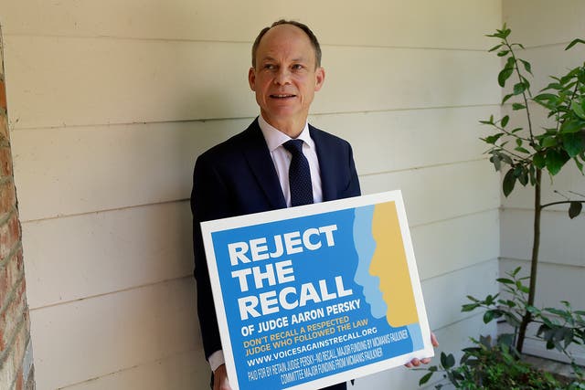 Judge Aaron Persky poses for a photo with a sign opposing his recall in Los Altos Hills, California