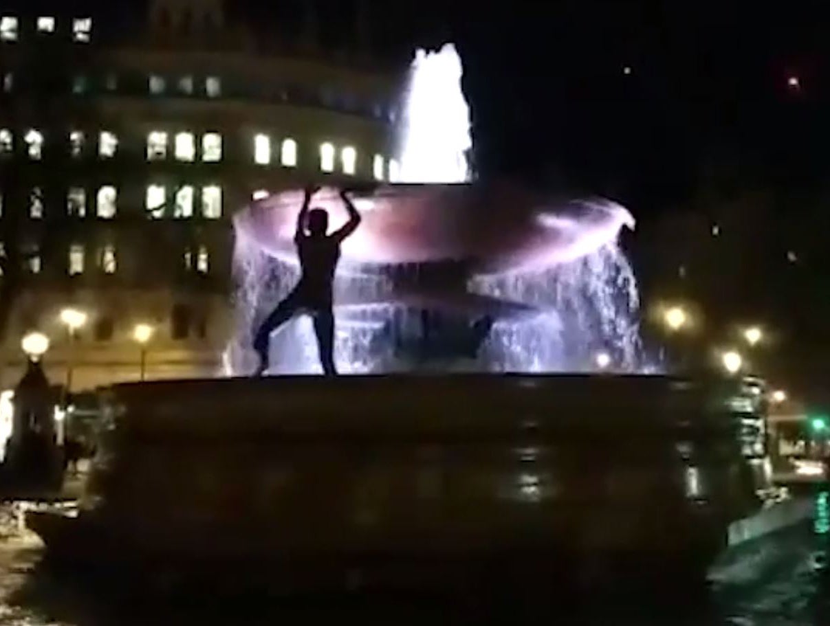 An Imperial College student climbs the fountains in Trafalgar Square