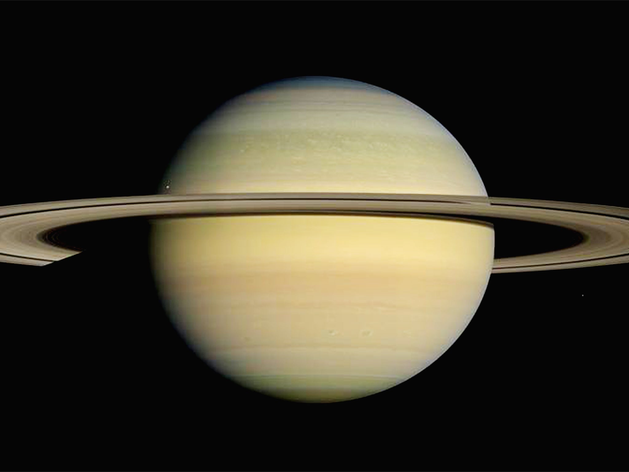 Saturn is girdled by brilliant appendages that would stretch almost all the way from the Earth to the Moon