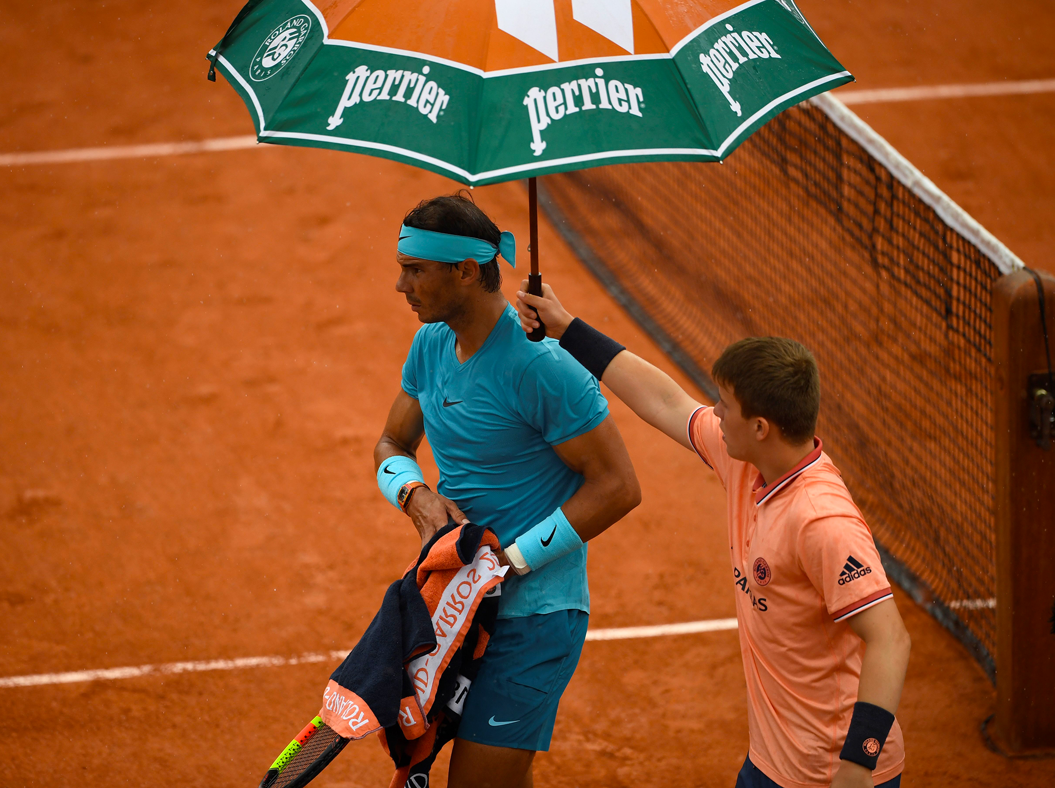 Rafael Nadal is shielded from the rain