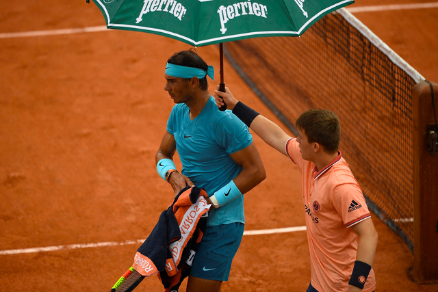 Rafael Nadal is shielded from the rain
