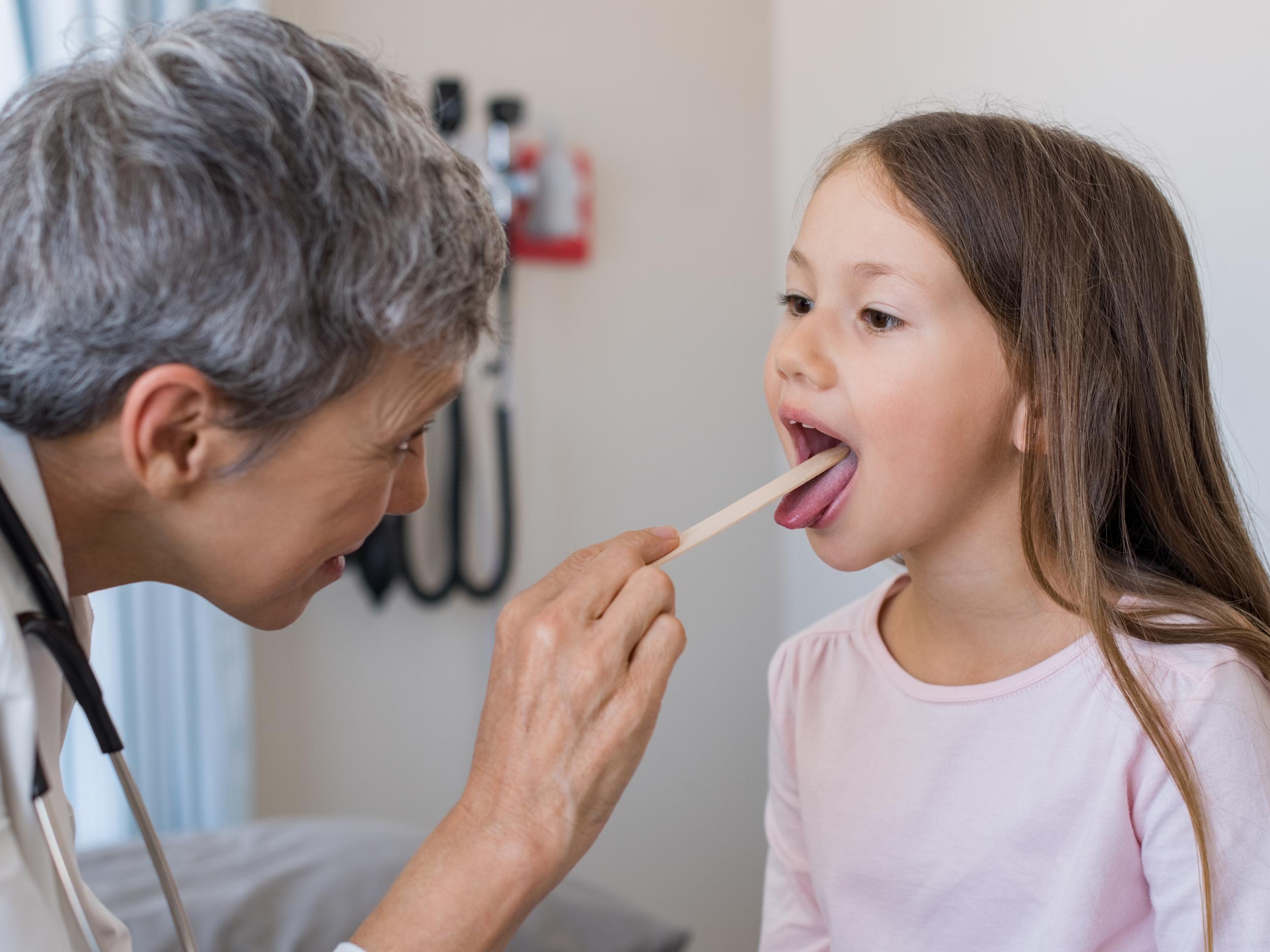 A GP inspecting a child’s tonsils