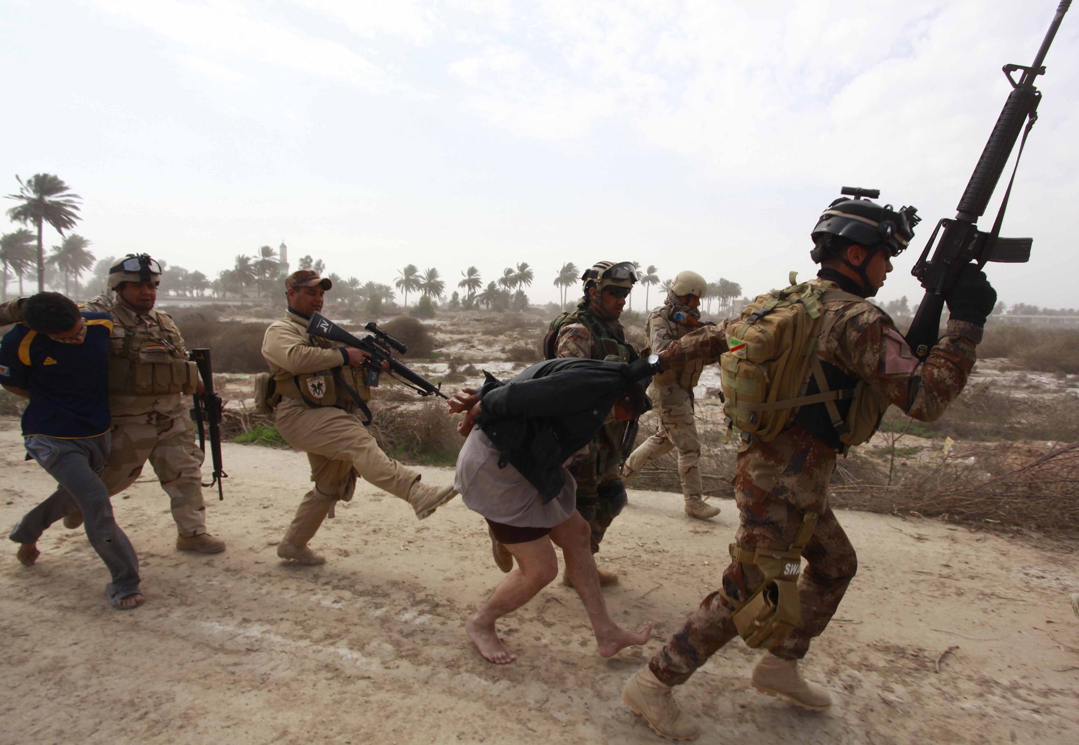 Members of the Iraqi security forces arrest a suspected Isis fighter in Jurf al Sakhar, 15 February 2014