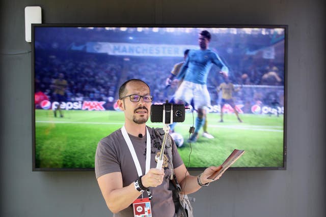 An industry personnel takes a selfie in front of a 'FIFA 19' screen during the Electronic Arts EA Play event at the Hollywood Palladium on June 9, 2018 in Los Angeles, California