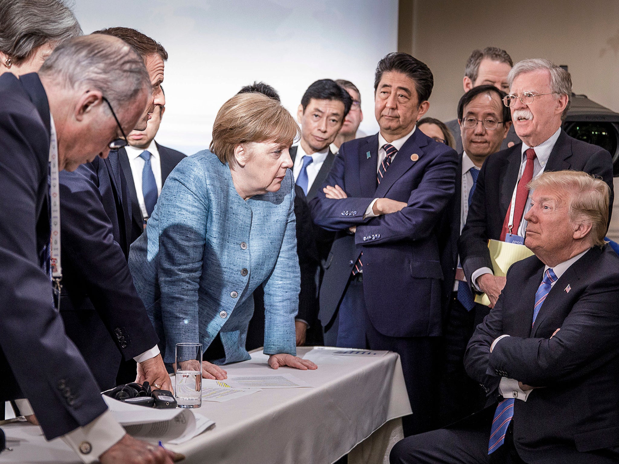 French President Emmanuel Macron, German Chancellor Angela Merkel and Japan's Prime Minister Shinzo Abe speaking to US Presidend Donald Trump during the second day of the G7 meeting in Charlevoix, Canada. Looking on is US National Security Advisor John R. Bolton.