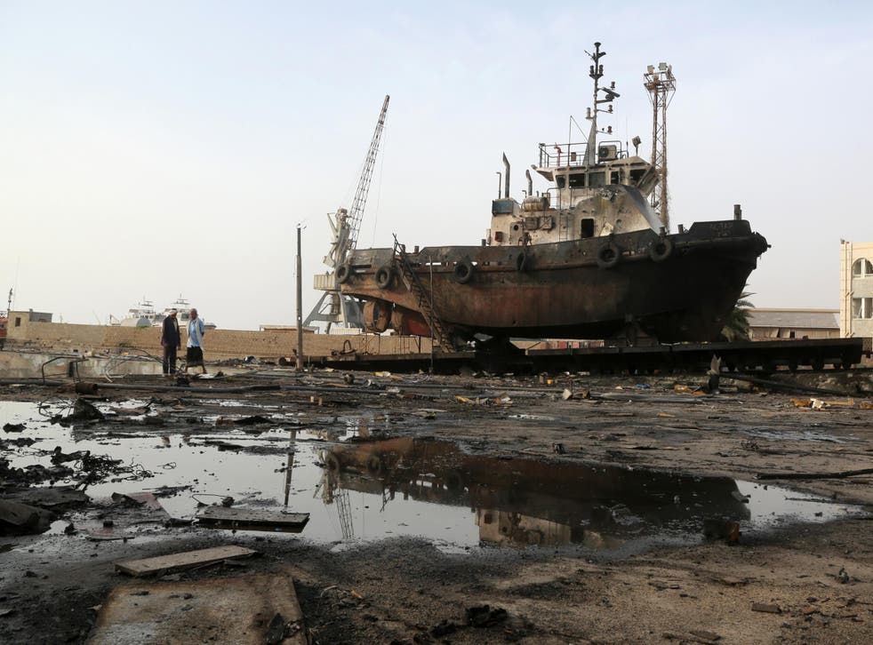 Workers inspect damage at the site of an airstrike on the maintenance hub at Hodeidah port