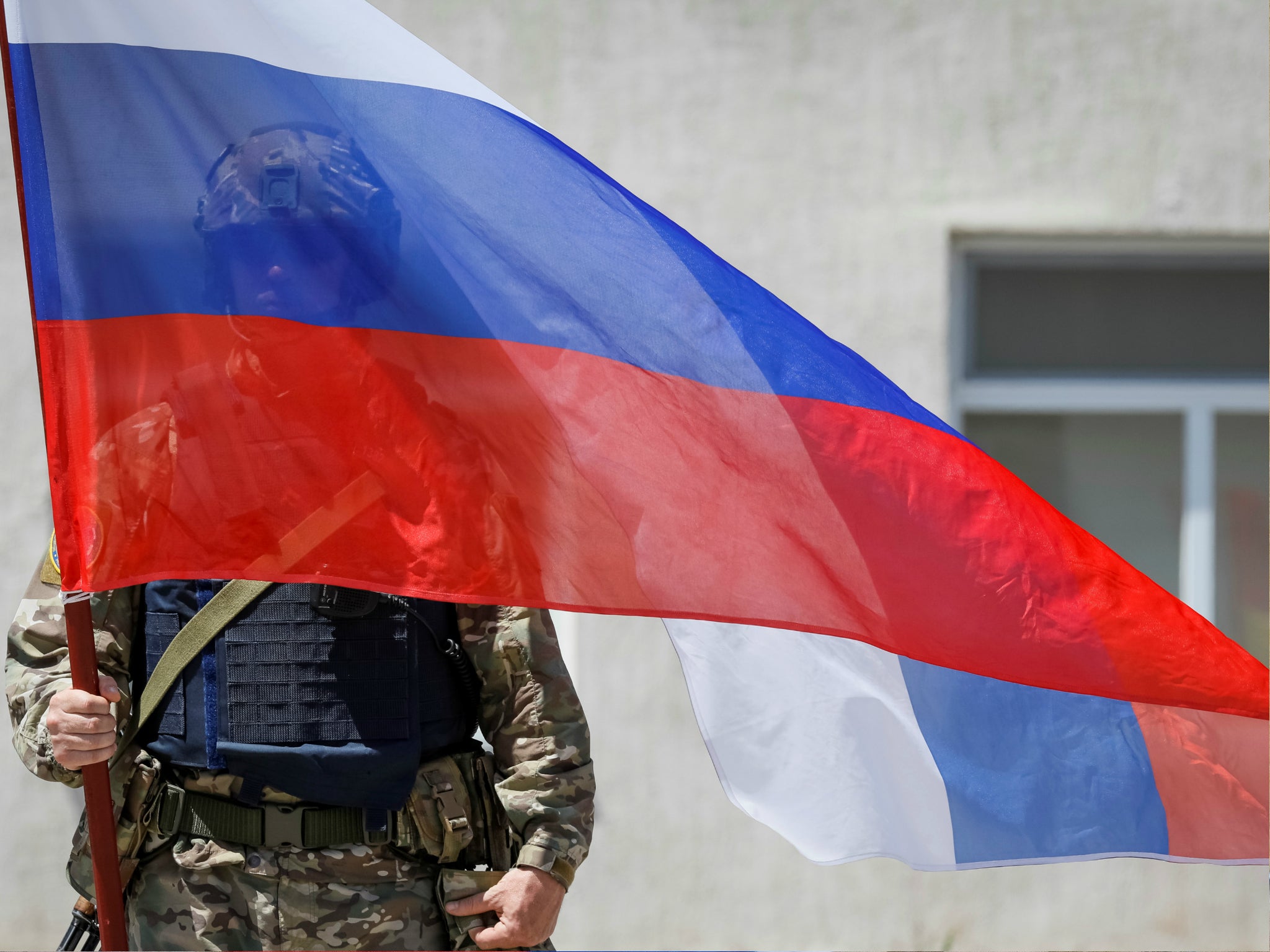 A member of Russia's special operations unit stands with a national flag. The US Treasury just imposed new sanctions on three Russians and five Russian companies for suspected cyber attacks.