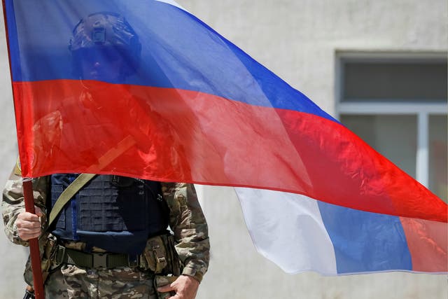 A member of Russia's special operations unit stands with a national flag. The US Treasury just imposed new sanctions on three Russians and five Russian companies for suspected cyber attacks.