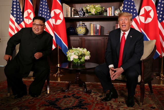 Donald Trump sits next to Kim Jong-un before their bilateral meeting at the Capella Hotel in Singapore