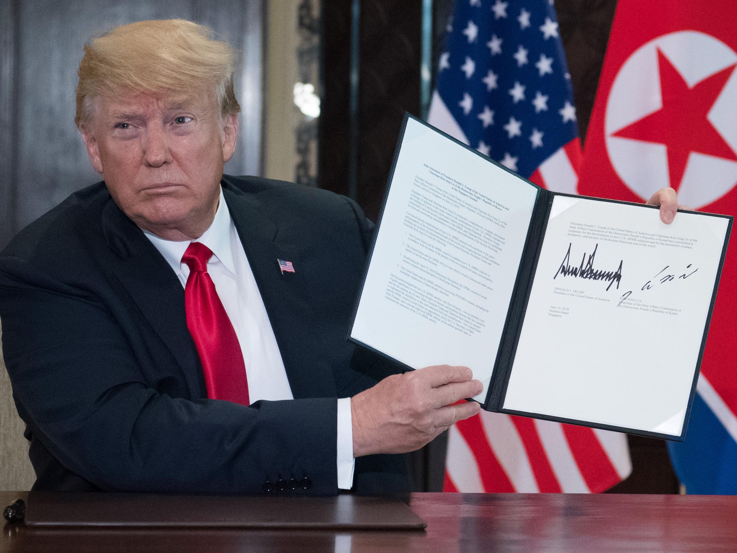 Donald Trump holds up a document signed by him and North Korea’s leader Kim Jong-un