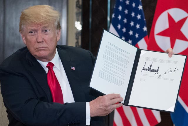 Donald Trump holds up a document signed by him and North Korea's leader Kim Jong-un